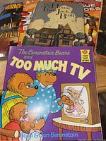 Group of children's books with varied titles showing cover art of The House That Jack Built and The Berenstain Bears and Too Much TV