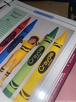 Page showing large Crayola crayons with person in bee costume, colorful craft project photograph.
