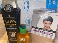 Three hair care products shown together: Schwarzkopf shampoo, Garnier oil, and weaving cap packaged.