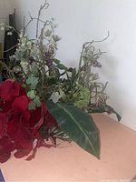 Close-up and side views of a fake plant arrangement showing detailed red flowers, green leaves, and berry-like clusters on branches