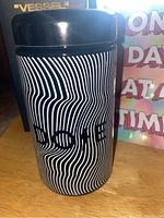 Black glass coffee container with white wavy lines and 'DOSE' text on the side, showing the outer design of the container.