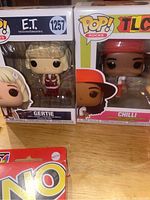 Two boxed Pop Rocks dolls, Chili and Gertie, with an opened UNO cards pack partially visible at bottom left corner
