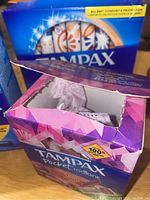 Opened Tampax Pocket Radiant box showing some tampons inside and purple floral packaging
