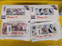 Photo showing multiple phone cases for iPhone 12, iPhone 7 Plus, and iPhone XS Max with floral and butterfly patterns in packaging.
