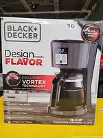 Boxed Black and Decker 12-cup coffeemaker showing product features and branding on packaging.