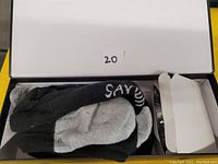 Open packaging box showing a pair of black and grey heated socks and two rechargeable batteries on the right side.