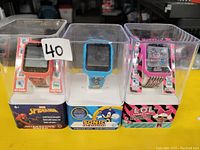 Photo of three kids digital watches in packaging themed Spiderman, Sonic the Hedgehog, and LOL Surprise.