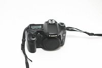 Front view of Canon EOS 40D camera body with body cap attached, camera strap visible