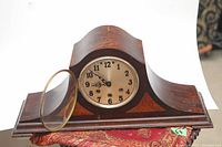 Front view of the wooden mantel clock with glass cover open, showing the clock face and hands
