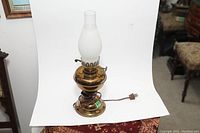 Full view of brass oil lamp converted to electric, showing frosted glass chimney and attached power cord.