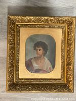 Front image of the oil painting depicting a woman, showing the ornate gold frame with detailed leaf and scroll motifs.