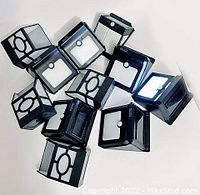 Photo showing a collection of eleven black outdoor solar LED lights with motion sensors, all in similar design and shape.