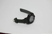 Side angle showing watch face, buttons and green silicone band with silver buckle.
