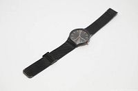 Full view of the black wrist watch showing the watch face with rose gold markings and mesh metal band laid flat.