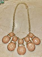 Close-up showing the necklace chain and the arrangement of peach moonstone-like cabochons on gold-tone bezels.