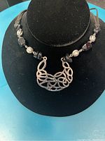 Photo of a silver-tone and onyx-like black stone bead necklace with an intricate silver-tone pendant on a black display bust.