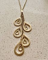 Close-up photo of the necklace pendants showing teardrop shapes with different textures on a stone surface.