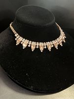 Front view of gold-tone crystal and sun topaz necklace on black velvet bust for display.