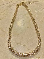Photo of a gold-tone necklace with round quartz crystals embedded along its length, laid flat on a marble surface.