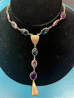 Clear front view of the necklace showing the oval-shaped blue and rose stones linked with gold-tone metal and hanging pendant.