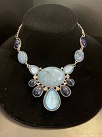Front view of the necklace showing large oval light blue moonstone centerpiece with surrounding smaller teardrop and oval blue stones.