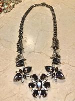 Photo of silver-tone necklace with black onyx and clear stones laid flat on a marble surface.