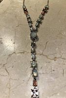 Close-up of the silver necklace with aquamarine and citrine stones on marble surface.