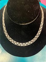Silver-tone necklace with clear rhinestones displayed on black velvet jewelry stand.