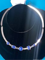 Front view of silver necklace with five indigo stones displayed on a black velvet bust, showing design details and stone placement.