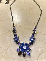 Front view of silver chain necklace featuring a floral design with blue and purple petals and clear iolite gem centers.