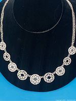 Silver necklace side with circular design links containing quartz-like stones