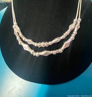 Full view of the double-strand silver bead necklace on a black velvet display.