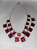 Front view of the gold-tone necklace with multiple faceted tourmaline pink stones in square and cushion cuts arranged along the chain.