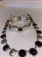 Silver and onyx necklace and bracelet set arranged to show detailing and materials.