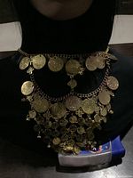 Front view of the gold finish belly dancing headpiece displayed on a black mannequin torso, showing multiple layers of gold coins hanging from chain links.