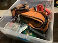 Photo showing orange fabric moving straps, plastic organizer box with small tools and hardware inside a clear plastic container