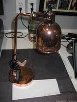 Copper finished desk lamp on desk showing adjustable arm and round base
