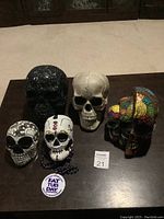 Five skulls arranged on table for lot overview showing variety of designs and styles