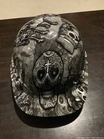 Front view of the Day of the Dead themed construction helmet, showing prominent decorated skull with cross icon on the forehead.