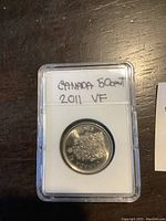 Front view of 2011 Canadian 50 cent coin in case with handwritten label reading 'CANADA 50 cent 2011 VF'.