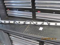 Full view showing the entire power bar resting on a black metal diamond plate surface with 10 outlets visible.