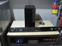 Samsung HW-B450 soundbar and wired subwoofer displayed on wooden shelf.
