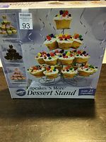 Front of the boxed Wilton Cupcakes 'N More Dessert Stand showing the product image and capacity of 23 cupcakes.