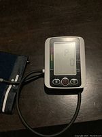 Close-up of digital blood pressure monitor unit showing LCD screen with buttons.
