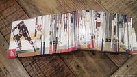 Image of a spread of hockey cards fanned out on a wooden surface showing various players in action and team logos, indicating quantity and condition.