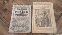 Pair of antique church songbooks from 1913 laid flat on wooden surface showing front covers.