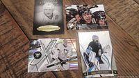Four hockey cards laid out on wooden surface including two of Evgeni Malkin and two of Marc Andre Fleury