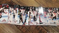 Partial collection of hockey trading cards with 32 cards arranged in overlapping stacks on a wooden surface.