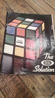 Front cover of vintage Rubik's Cube The Ideal Solution book showing Rubik's Cube illustration and title text, worn condition visible.
