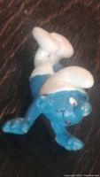 Front view of vintage 1980s Smurf figure in sliding pose showing facial features and body position